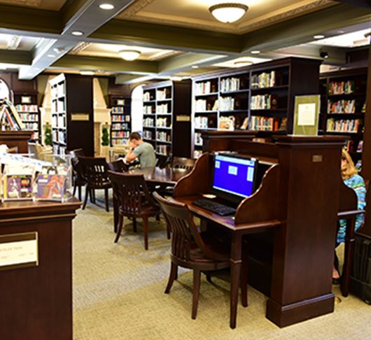 people sitting and reading and looking up books at the library