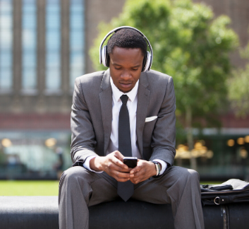 young professional sitting outside listening to device with headphones