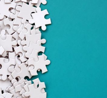 Teal background with scattered white puzzle pieces on the left side.