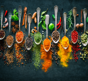 Several spoons with herbs on them with a black background