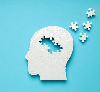 Light blue background with a human head shape comprised of white puzzle pieces. 